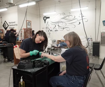 TWO STUDENTS PRACTICE GEL POLISH APPLICATION.